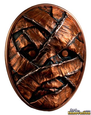 Copper oval badge of a wrapped mummy face with small round eyes peering out