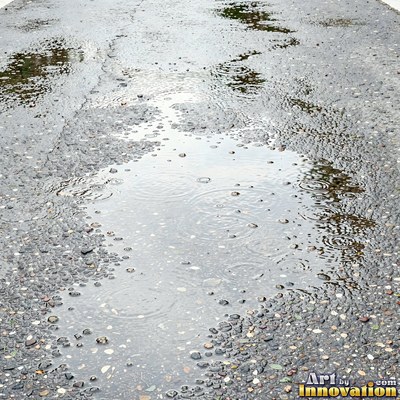 Asphalt pavement marked with oil stains and tire scuffs in medium gray