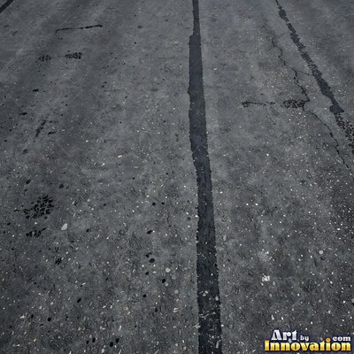 Wet asphalt glistening with small puddles in a greenish gray tone