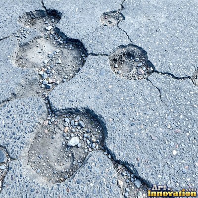 Asphalt pavement marked with oil stains and tire scuffs in medium gray