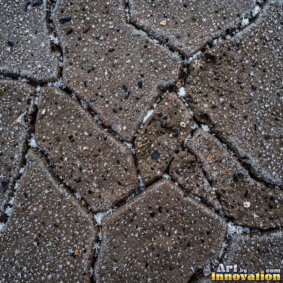 Asphalt pavement marked with oil stains and tire scuffs in medium gray