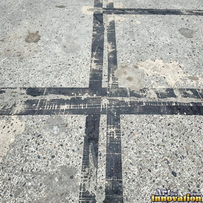 Asphalt pavement marked with oil stains and tire scuffs in medium gray