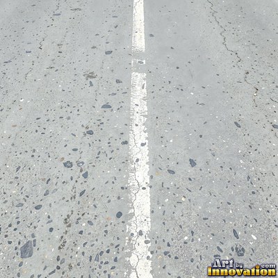 Wet asphalt glistening with small puddles in a greenish gray tone
