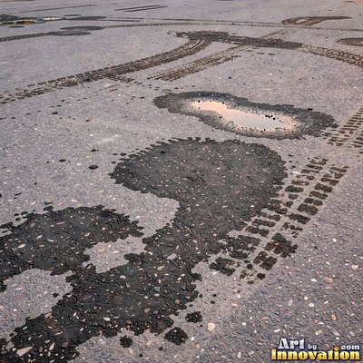 Wet asphalt glistening with small puddles in a greenish gray tone