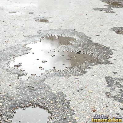 Wet asphalt glistening with small puddles in a greenish gray tone