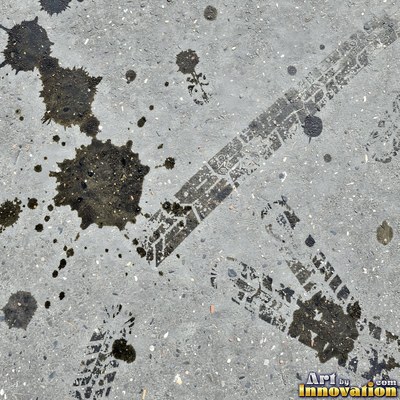 Asphalt pavement marked with oil stains and tire scuffs in medium gray