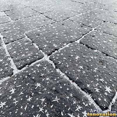 Wet asphalt glistening with small puddles in a greenish gray tone