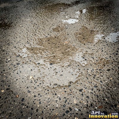 Asphalt pavement marked with oil stains and tire scuffs in medium gray
