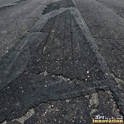 Wet asphalt glistening with small puddles in a greenish gray tone