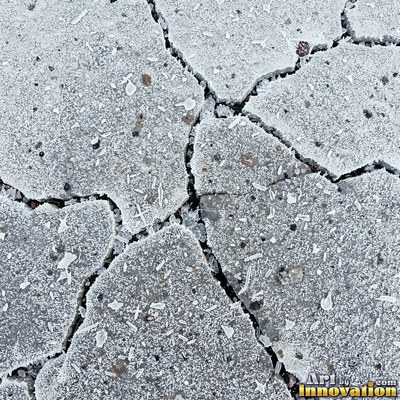 Asphalt pavement marked with oil stains and tire scuffs in medium gray