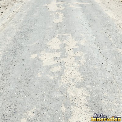 Asphalt pavement marked with oil stains and tire scuffs in medium gray
