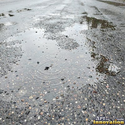 Wet asphalt glistening with small puddles in a greenish gray tone