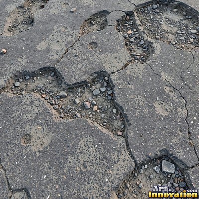 Asphalt pavement marked with oil stains and tire scuffs in medium gray