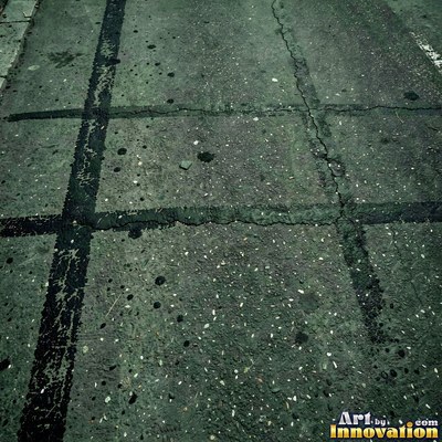 Asphalt pavement marked with oil stains and tire scuffs in medium gray