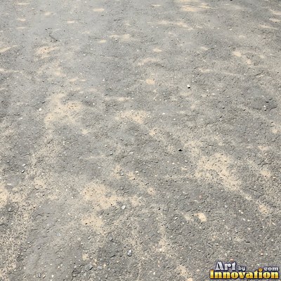 Wet asphalt glistening with small puddles in a greenish gray tone