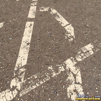 Asphalt pavement marked with oil stains and tire scuffs in medium gray
