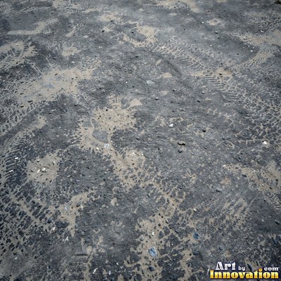 Asphalt pavement marked with oil stains and tire scuffs in medium gray