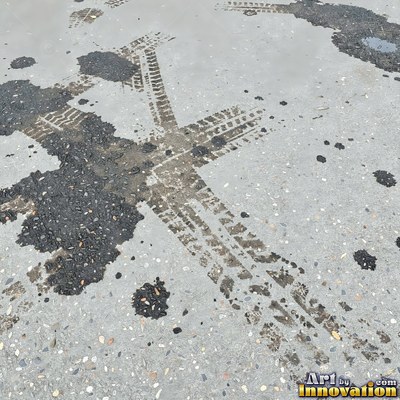Wet asphalt glistening with small puddles in a greenish gray tone