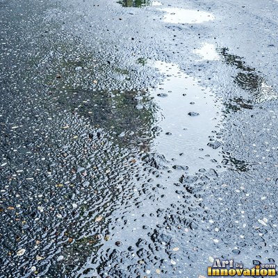 Wet asphalt glistening with small puddles in a greenish gray tone