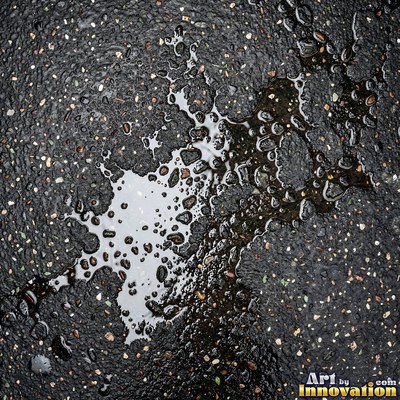 Asphalt pavement marked with oil stains and tire scuffs in medium gray