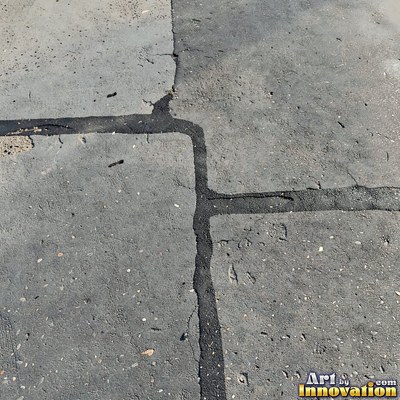 Asphalt pavement marked with oil stains and tire scuffs in medium gray