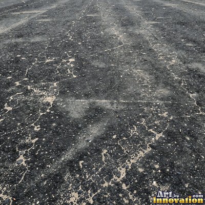 Wet asphalt glistening with small puddles in a greenish gray tone