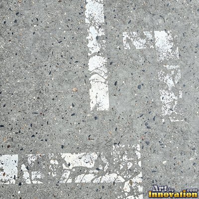 Asphalt pavement marked with oil stains and tire scuffs in medium gray
