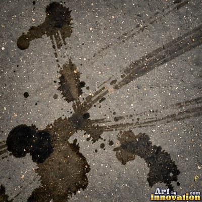 Asphalt pavement marked with oil stains and tire scuffs in medium gray