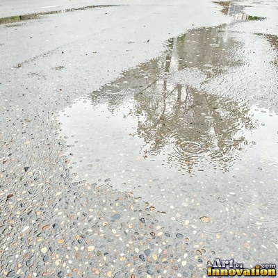 Asphalt pavement marked with oil stains and tire scuffs in medium gray