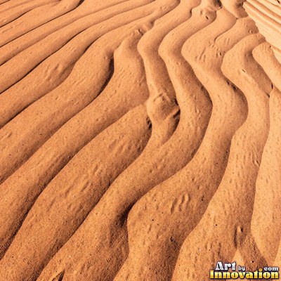 Pale golden wet sand with a shiny surface and tiny pits