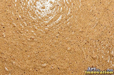 Pale golden wet sand with a shiny surface and tiny pits