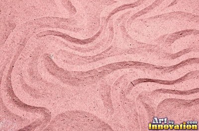 Pink sand marked with small swirls carved by the wind