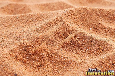 Pale golden wet sand with a shiny surface and tiny pits