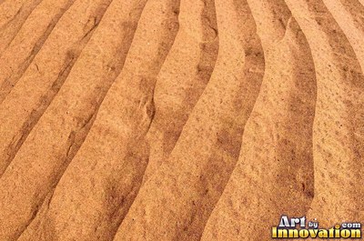 Pink sand marked with small swirls carved by the wind