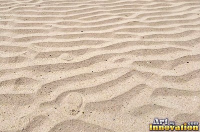 Pale golden wet sand with a shiny surface and tiny pits