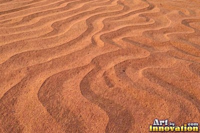 Pale golden wet sand with a shiny surface and tiny pits