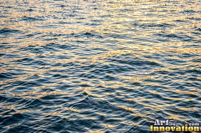 Choppy water surface of many small waves with gold reflections
