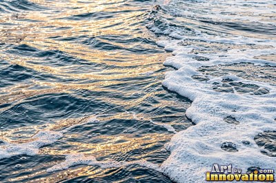 Choppy water surface of many small waves with gold reflections