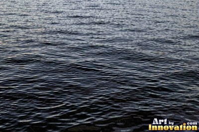 Choppy water surface of many small waves with gold reflections
