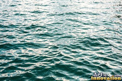 Choppy water surface of many small waves with gold reflections