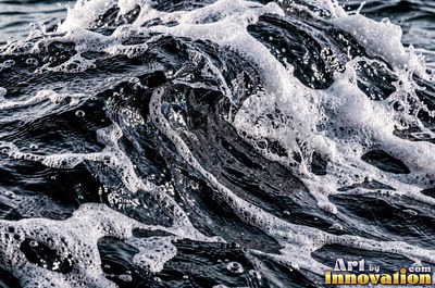 Close wave crest with white foam on inky blue black water