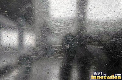 Polished satin chrome with a fine scratch pattern catching the glare