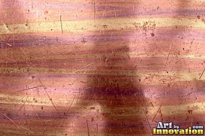 Oxidized copper with a mottled dark surface and bright scratches