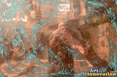 Oxidized copper with a mottled dark surface and bright scratches