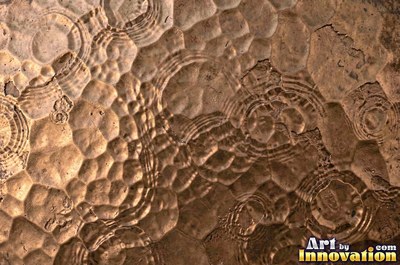 Large shallow hammer marks catching light like ripples on water