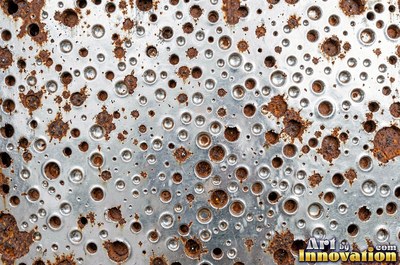 Heavily rusted steel plate with flaking orange scale and dark pits