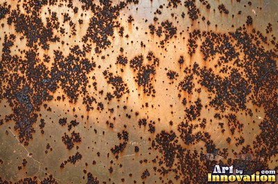 Heavily rusted steel plate with flaking orange scale and dark pits