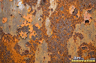 Heavily rusted steel plate with flaking orange scale and dark pits