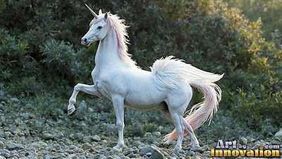Snow-white unicorn stands on a stony ground near green bushes