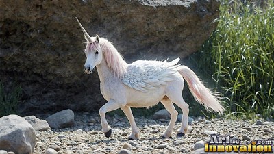 A small winged unicorn trots over stones with pale pink hair in the bright sun